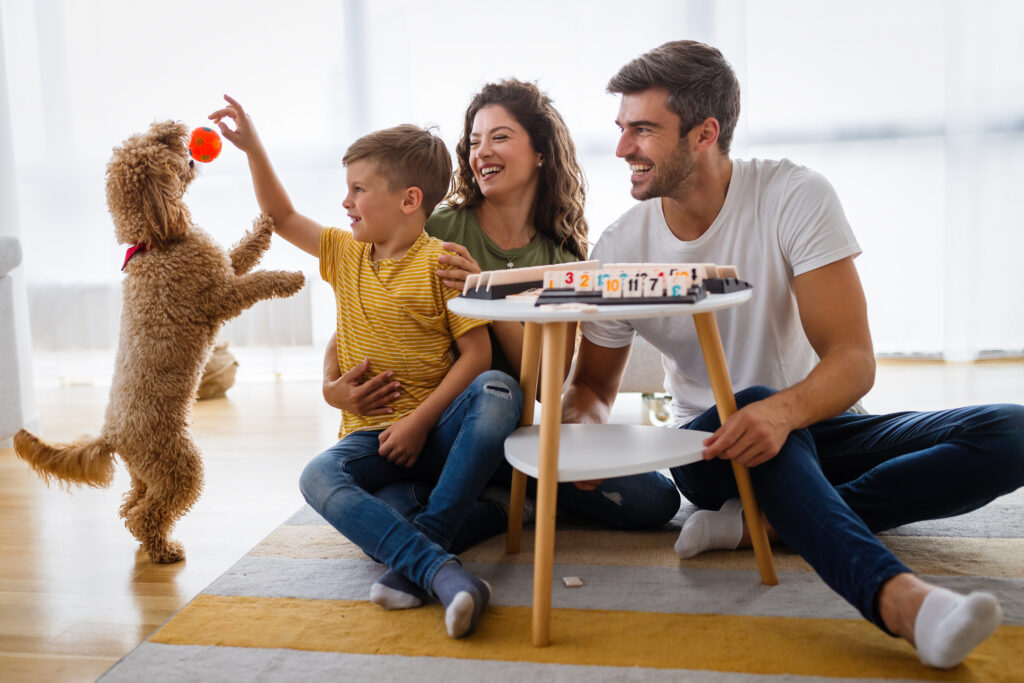 Happy family having fun time, playing together at home with dog