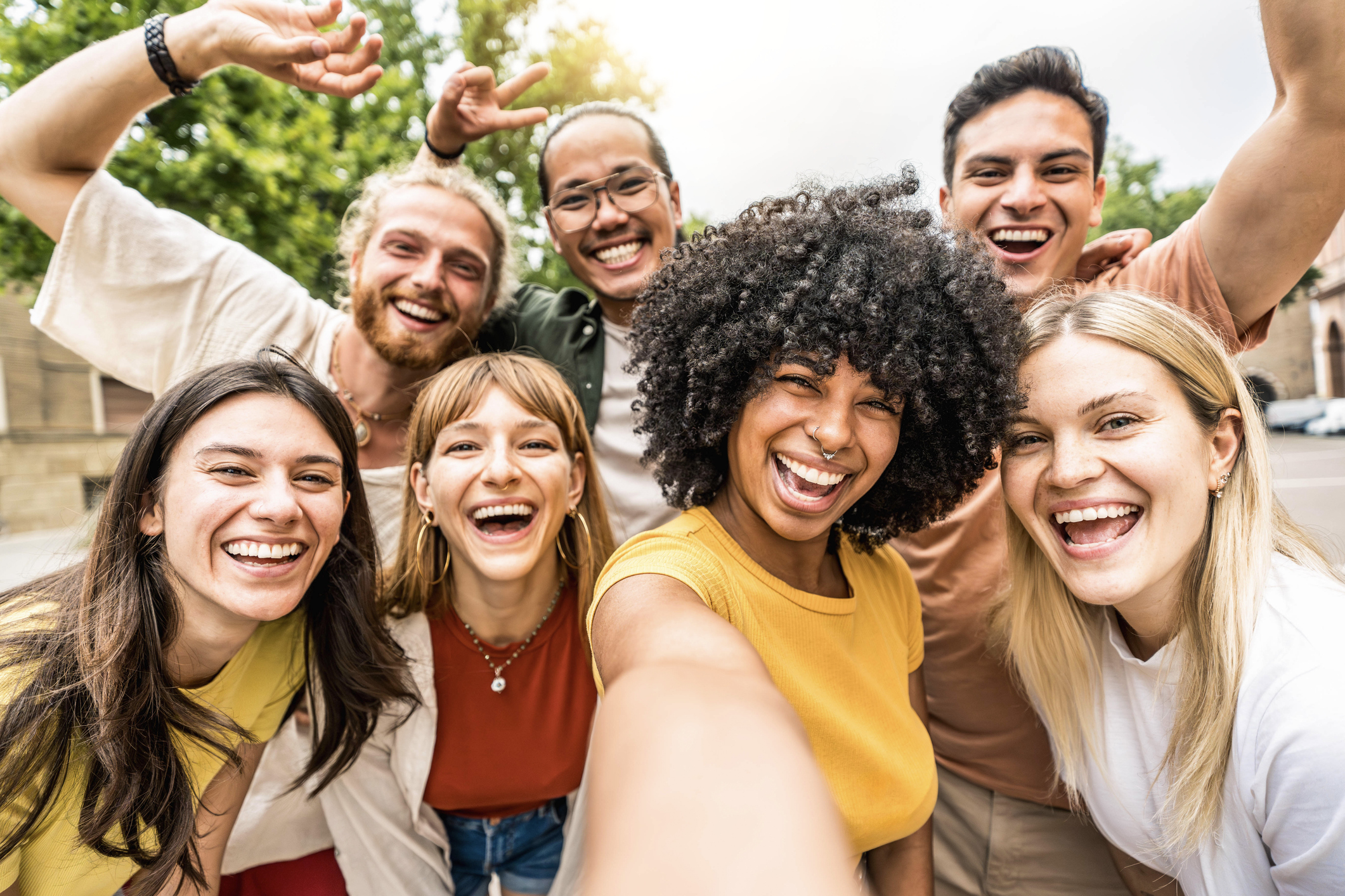Multicultural friends smiling at camera together outside Happy young people taking selfie with smart mobile phone device walking on city street Youth community and technology concept